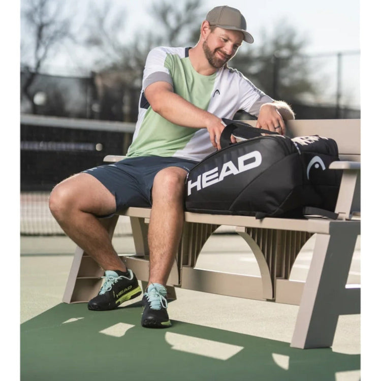 Jugador sentado en un banco de pista con la bolsa Radach Sports Head Pro Pickleball negra con logo blanco