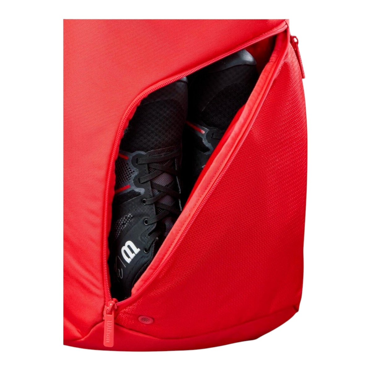 Detalle del compartimento para calzado en la mochila Radach Sports Wilson Padel Tour roja con zapatillas negras