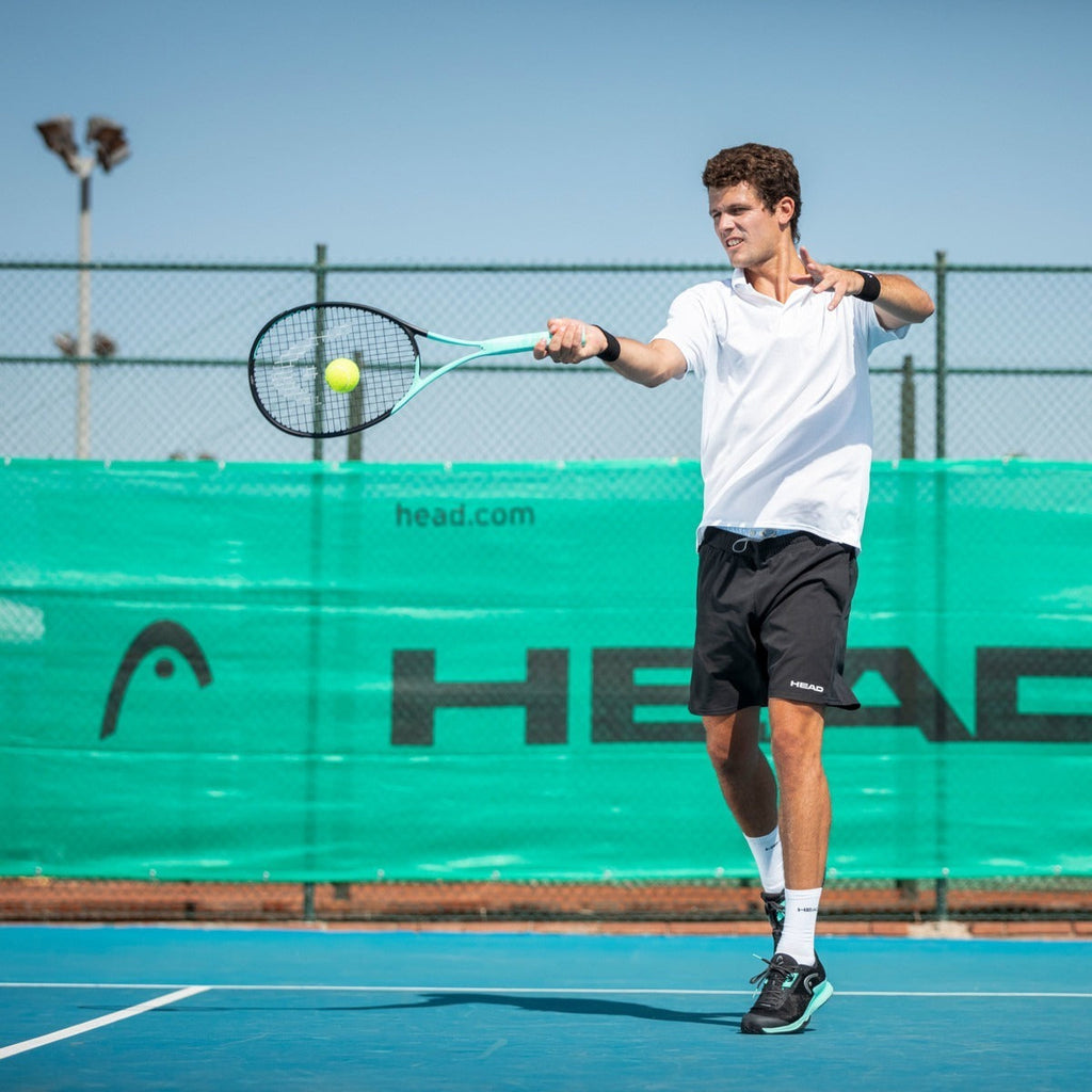 Jugador de tenis Radach Sports usando raqueta Head Boom MP 2022 de color turquesa en una pista dura al aire libre