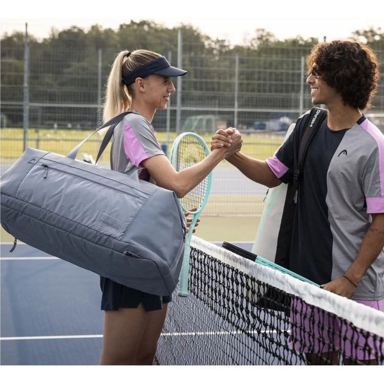 Jugadora de tenis con raquetero Radach Sports Head Tour Duffle Bag gris saludando a su compañero en la pista