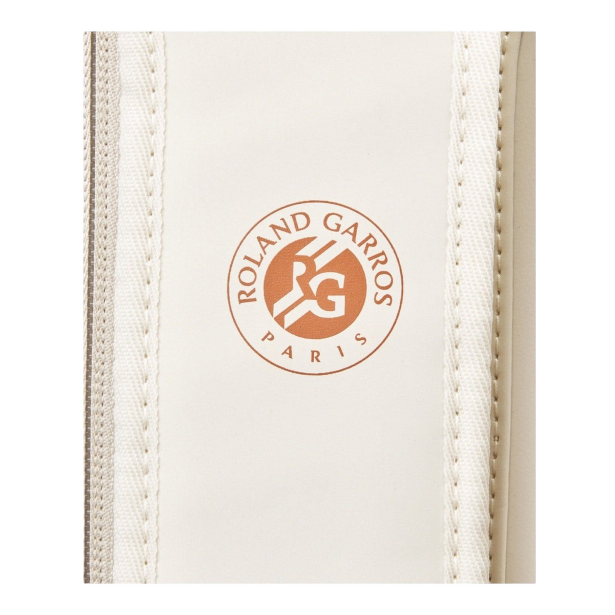 Detalle del logo oficial de Roland Garros en color terracota sobre fondo crema en raquetero Radach Sports Wilson