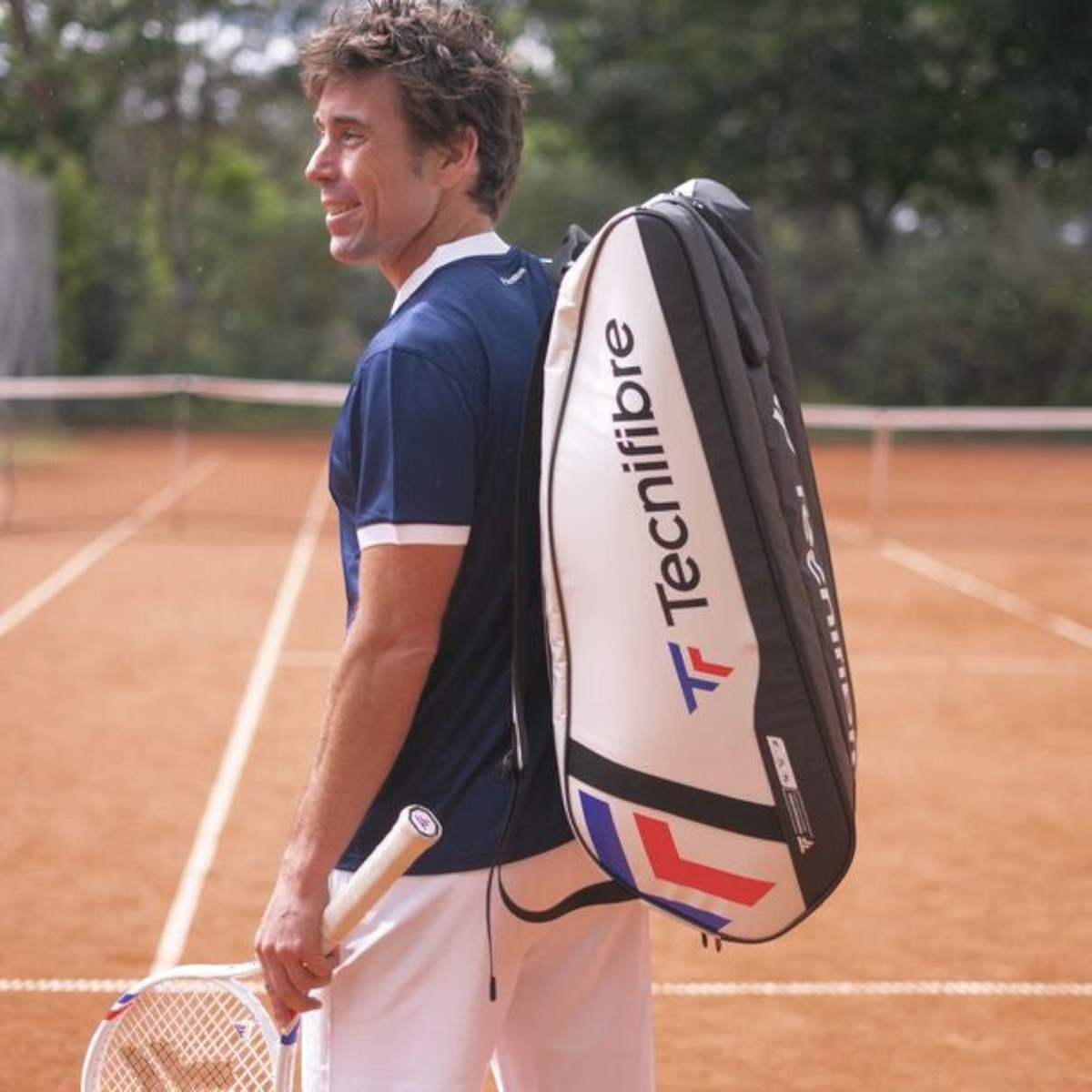 Jugador de tenis con raquetero Radach Sports Tecnifibre Tour Endurance blanco de 12 raquetas en pista de arcilla